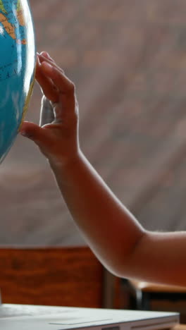 Vídeo-Vertical-De-La-Mano-De-Un-Niño-Tocando-Un-Globo-Terráqueo-En-Un-Salón-De-Clases