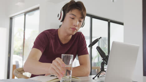 Asiatischer-Junge-Mit-Kopfhörern-Spricht-über-Ein-Professionelles-Mikrofon,-Um-Zu-Hause-Einen-Audio-Podcast-Aufzunehmen