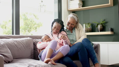 Glückliche-Afroamerikanische-Mutter,-Tochter-Und-Großmutter-Umarmen-Sich-Auf-Der-Couch-Und-Lachen,-Zeitlupe