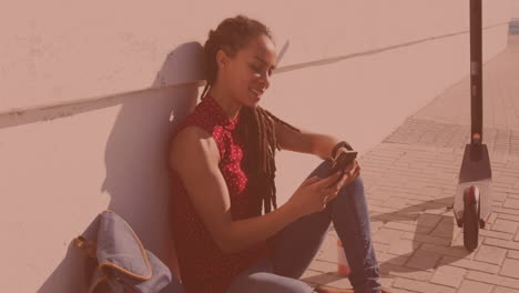 Biracial-woman-using-a-smartphone-sitting-on-the-side-of-the-street