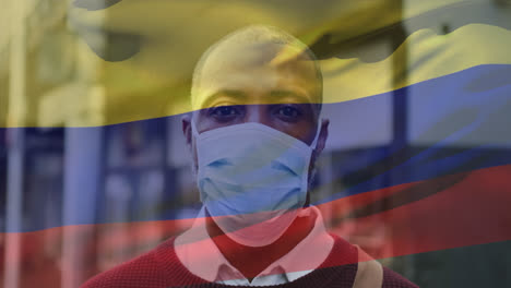 Animation-of-waving-colombia-flag-over-portrait-of-african-american-man-wearing-face-mask-on-street