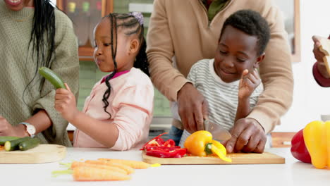 Happy-african-american-parents-and-children-chopping-vegetables-in-kitchen,-slow-motion