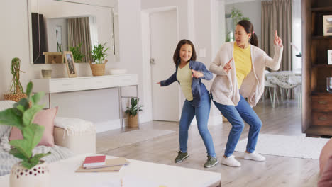 Video-Einer-Glücklichen-Asiatischen-Mutter-Und-Tochter,-Die-Im-Wohnzimmer-Tanzen