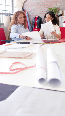 Felices-Y-Diversas-Diseñadoras-De-Moda-Discutiendo-Telas-En-El-Estudio,-Cámara-Lenta,-Vertical.