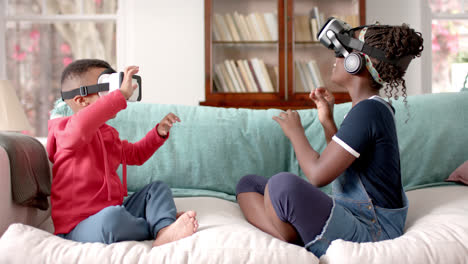 African-american-sister-and-brother-using-vr-headset-in-living-room,-slow-motion