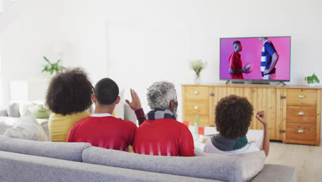Biracial-family-watching-tv-with-diverse-male-rugby-players-with-ball-on-screen