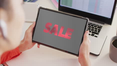 Caucasian-woman-at-desk-using-tablet,-online-shopping-during-sale,-slow-motion