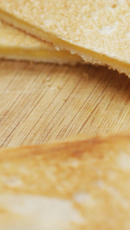 Video-of-slices-of-toasted-cheese-white-bread-sandwiches-on-wooden-chopping-board-background