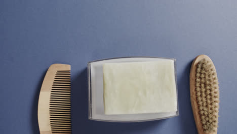 Close-up-of-soap,-brush-and-comb-on-blue-background