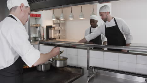 Group-of-diverse-male-chefs-preparing-meals-in-kitchen,-slow-motion