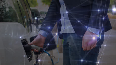 Animation-of-connecting-dots-over-caucasian-man-inserting-ev-plug-into-car-at-charging-station