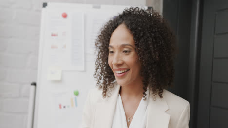 Happy-biracial-businesswoman-by-whiteboard-talking-at-office-meeting,-in-slow-motion