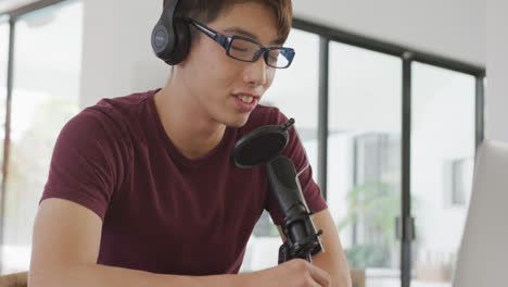 Asiatischer-Junge-Mit-Kopfhörern-Spricht-über-Ein-Professionelles-Mikrofon,-Um-Zu-Hause-Einen-Audio-Podcast-Aufzunehmen