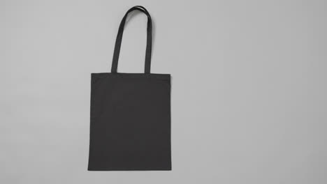 Nahaufnahme-Einer-Schwarzen-Tasche-Auf-Grauem-Hintergrund,-Mit-Kopierraum,-Zeitlupe