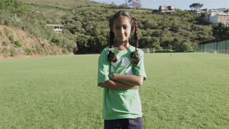 Biracial-girl-stands-confidently-on-a-soccer-field-wearing-a-green-recycling-t-shirt
