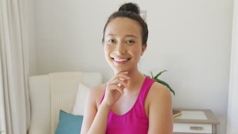 Portrait-of-happy-asian-woman-looking-at-camera-and-smiling-in-bedroom,-in-slow-motion