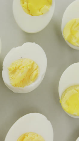 Video-of-overhead-view-of-halves-of-hard-boiled-eggs-on-grey-background