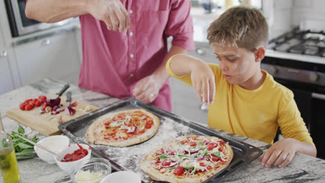 Feliz-Abuelo-Caucásico-Y-Nieto-Haciendo-Pizza-En-La-Cocina,-Cámara-Lenta