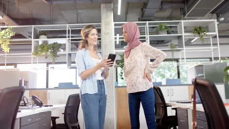 Happy-diverse-creative-female-colleagues-in-discussion-using-smartphone-in-office,-slow-motion