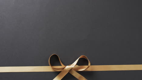 Video-of-gold-gift-ribbon-and-bow-with-copy-space-on-black-background