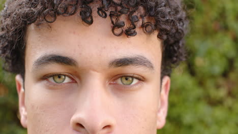 Biracial-man-face-close-up-and-looking-into-camera-outdoors,-slow-motion