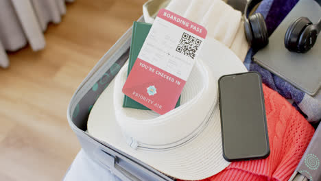 Close-up-of-luggage-with-a-ticket,-passport,-smartphone-and-headphones-in-suitcase