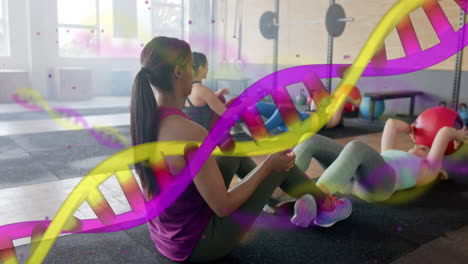Animation-of-dna-strands-over-diverse-women-cross-training-in-pairs-with-medicine-balls-at-gym