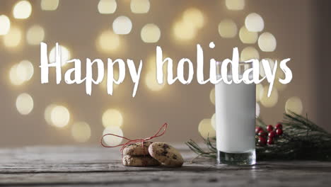 Happy-holidays-text-in-white-over-christmas-cookies-and-milk-over-bokeh-lights