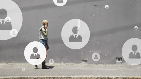 Animation-of-social-media-icons-over-biracial-woman-walking-and-using-smartphone