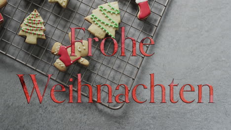 Frohe-weihnachten-text-in-red-over-decorated-christmas-cookies-on-grey-background
