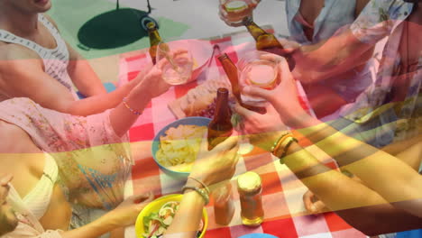 Composite-video-of-waving-germany-rica-over-diverse-friends-toasting-drinks-having-lunch-in-park