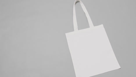 Close-up-of-white-bag-on-grey-background,-with-copy-space,-slow-motion