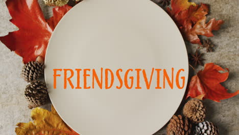 Animation-of-friendsgiving-text-over-cutlery-and-autumn-leaves-over-grey-background