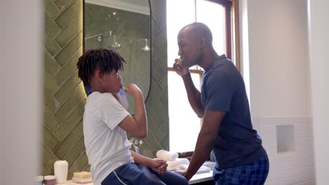 Afroamerikanischer-Vater-Und-Sohn-Putzen-Sich-Zu-Hause-Im-Badezimmer-Die-Zähne,-Zeitlupe
