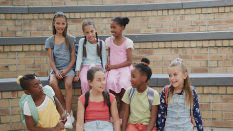 Portrait-of-happy-diverse-schoolgirls-on-stairs-in-slow-motion-at-elementary-school