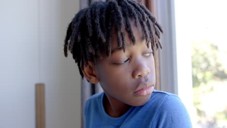 Nachdenklicher-Afroamerikanischer-Junge,-Der-Zu-Hause-Durch-Das-Fenster-Schaut,-Zeitlupe