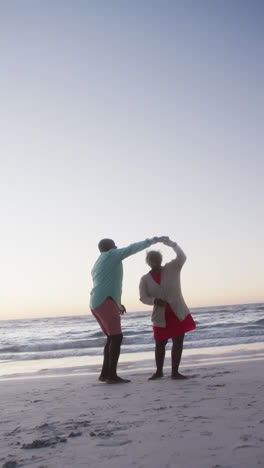 Video-Vertical-De-Una-Pareja-Afroamericana-Bailando-En-La-Playa,-En-Cámara-Lenta