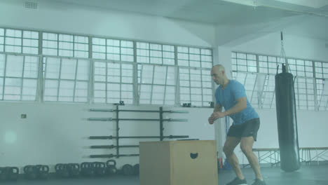 Animation-of-lens-flares-over-caucasian-bald-man-practicing-plyometric-exercise-on-box-in-gym