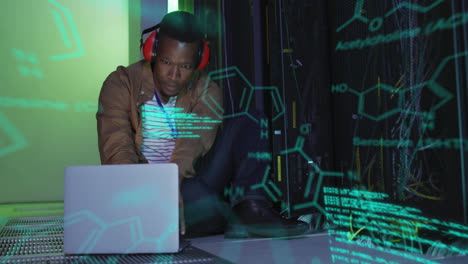 Animation-of-molecule-structures,-computer-language,-african-american-man-with-laptop-in-server-room