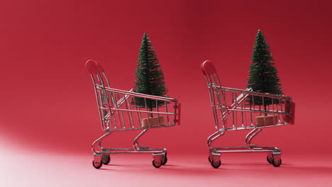 Video-of-shopping-trolley-with-christmas-trees-and-copy-space-on-red-background