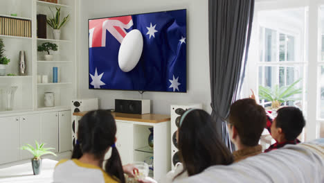 Familia-Asiática-Viendo-Televisión-Con-Pelota-De-Rugby-En-La-Bandera-De-Australia-En-La-Pantalla