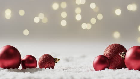 Video-of-red-baubles-christmas-decorations-with-copy-space-on-snow-background