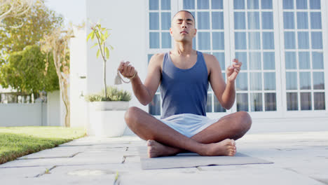Hombre-Birracial-Enfocado-Practicando-Meditación-De-Yoga-En-Un-Jardín-Soleado,-Cámara-Lenta