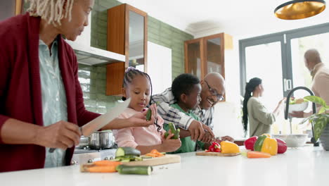Happy-african-american-grandparents-and-grandchildren-chopping-vegetables-in-kitchen,-slow-motion
