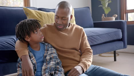 African-american-father-and-son-embracing,-talking-and-high-fiving-at-home,-slow-motion