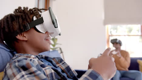Afroamerikanischer-Vater-Und-Sohn-Spielen-Videospiele-Mit-VR-Headsets-Zu-Hause,-Zeitlupe