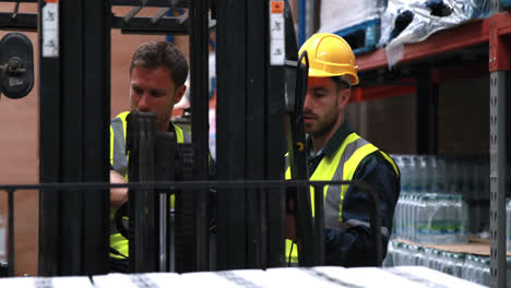 Warehouse-worker-talking-with-forklift-driver-