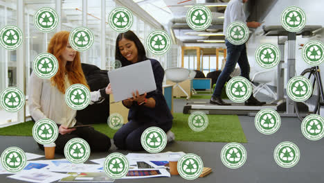 Animation-of-recycling-icons-over-happy-diverse-female-coworkers-in-office
