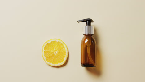 Close-up-of-lemon-slice-and-soap-bottle-on-beige-background-with-copy-space