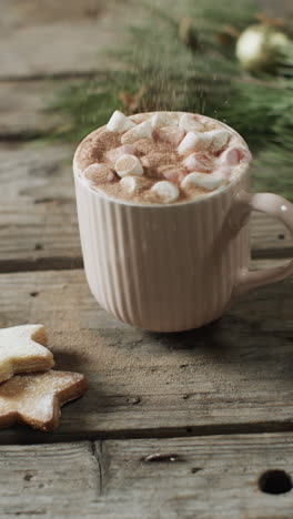 Vertical-video-of-mug-of-christmas-chocolate-with-marshmallows-and-copy-space-on-wooden-background